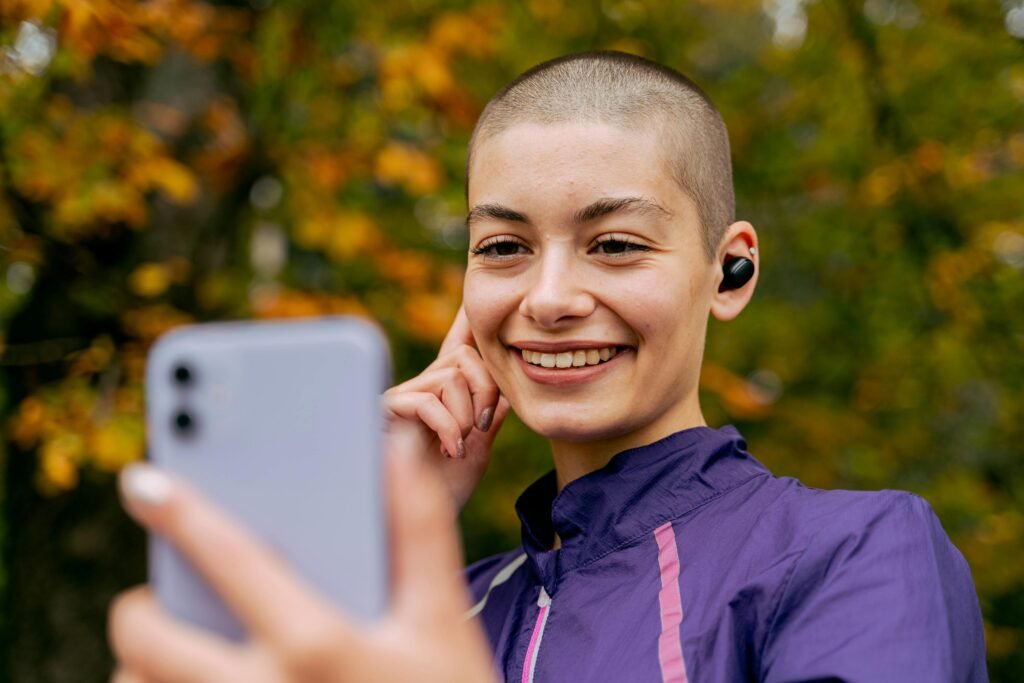 Smiling woman in autumn park using smartphone for a video call.