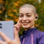 Smiling woman in autumn park using smartphone for a video call.