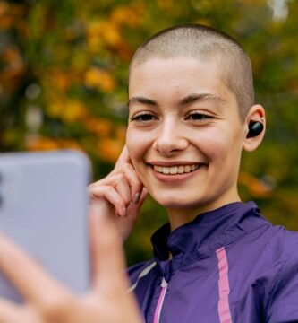 Smiling woman in autumn park using smartphone for a video call.