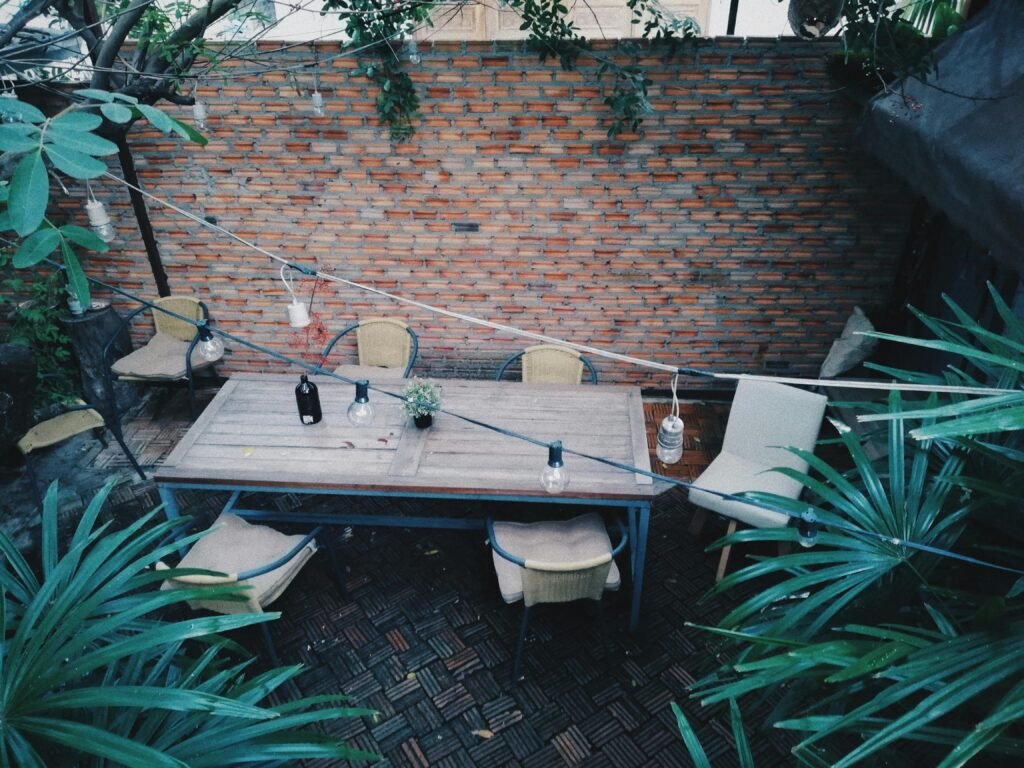 Cozy outdoor patio with wooden table and chairs against a rustic brick wall.